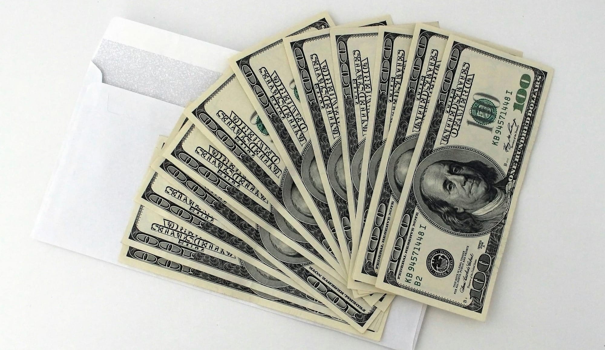 Stack of $100 bills fanned out from a white envelope, symbolizing TikTok Creator Rewards payouts