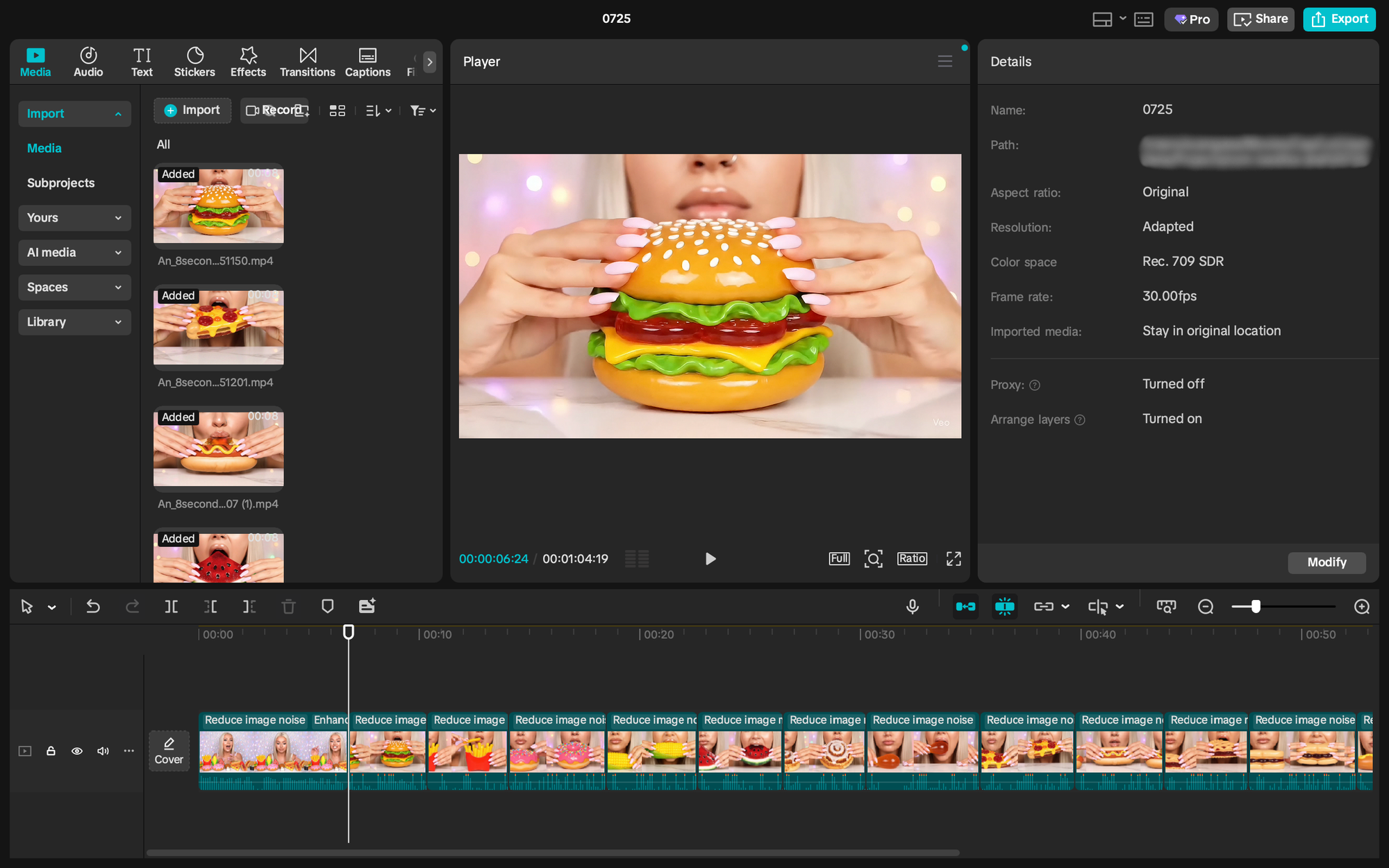A screenshot of a video editing interface. The central preview window shows a close-up of a person's hands holding a highly realistic, vibrant orange and green hamburger with a bright yellow cheese slice and red tomatoes. On the left sidebar, there are options for "Media," "Audio," "Text," "Stickers," "Effects," "Transitions," and "Captions." Below "Media," imported video clips are visible, including one titled "An_Bacon_33150.mp4." On the right, a "Details" panel displays information about the current video, such as "Resolution: Adapted," "Color space: Rec. 709 SDR," and "Frame rate: 30.00fps." A timeline at the bottom shows various video segments with labels like "Reduce image noise" and "Enhance."